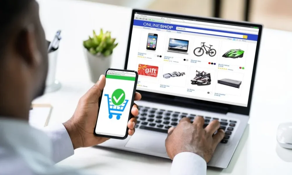 A modern laptop on a desk showing an online store homepage with products and a shopping cart