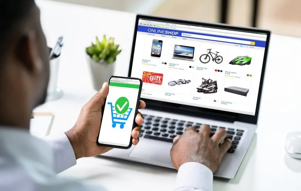 A modern laptop on a desk showing an online store homepage with products and a shopping cart