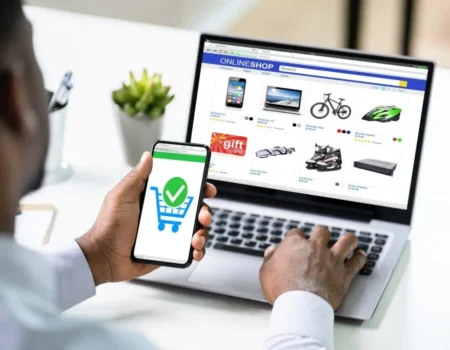 A modern laptop on a desk showing an online store homepage with products and a shopping cart