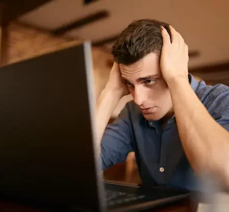 frustrated freelancer holding head while working on laptop