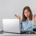 Freelancer looking frustrated while using Fiverr platform, with declining sales graph on screen – representing common Fiverr mistakes that hurt earnings