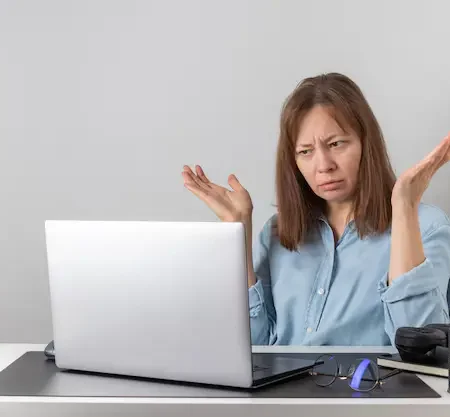 Freelancer looking frustrated while using Fiverr platform, with declining sales graph on screen – representing common Fiverr mistakes that hurt earnings